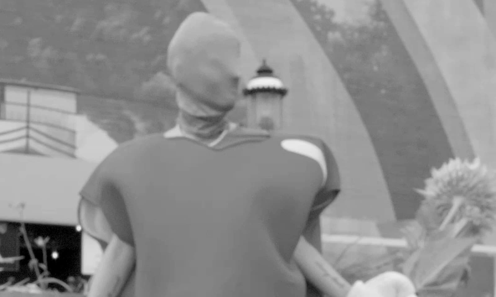 Still frame from video with shrouded figure